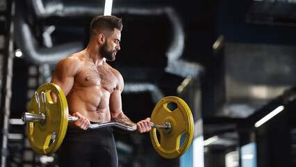 Handsome naked weightlifter lifting heavy barbell in gym, free space