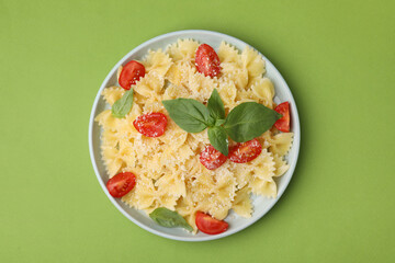 Tasty pasta with tomato, cheese and basil on green table, top view