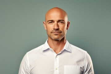 Portrait of a content man in his 40s wearing a simple cotton shirt while standing against solid color backdrop