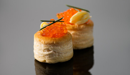 Tartlets with red caviar close up. Gourmet food close up, appetizer. Close-up salmon or trout caviar over gray background with reflection. Delicatessen. Gourmet food. Texture of caviar. Seafood 