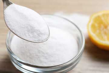 Taking baking soda from bowl at wooden table, closeup