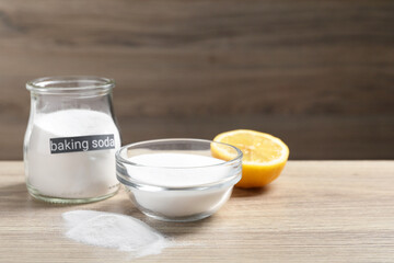 Baking soda and lemon on wooden table, space for text