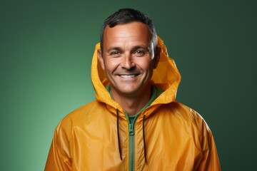 Fototapeta premium Portrait of a smiling man in his 40s wearing a lightweight packable anorak on solid color backdrop
