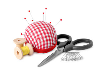 Pincushion with sewing pins, scissors, spools and thread isolated on white