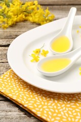 Rapeseed oil in gravy boats and beautiful yellow flowers on wooden table