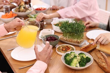 Friends eating vegetarian food at wooden table indoors, closeup