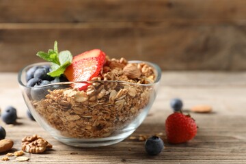 Tasty granola with berries, nuts and mint on wooden table