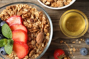 Tasty granola with berries, nuts and mint on wooden table, flat lay