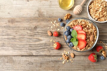 Tasty granola with berries, nuts and mint on wooden table, flat lay. Space for text