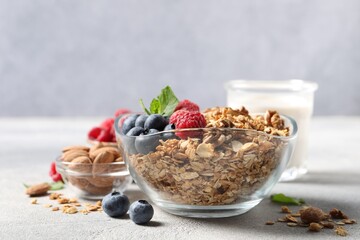 Tasty granola with berries, nuts and mint on grey table