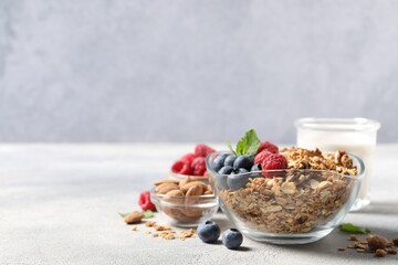 Tasty granola with berries, nuts and mint on grey table. Space for text