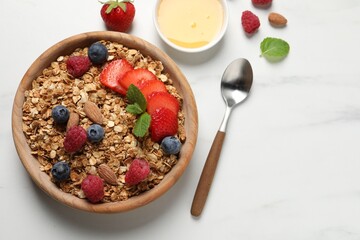 Tasty granola with berries, nuts and mint on white table, flat lay