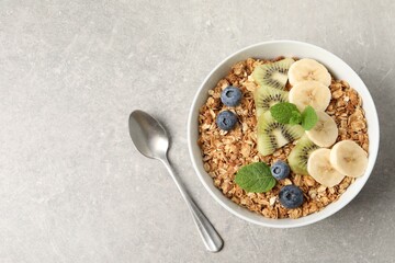 Tasty granola with fresh fruits on grey table, top view. Space for text