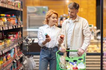 Happy European family shopping groceries in supermarket, choose what to buy, walking with trolley,...