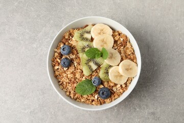 Tasty granola with fresh fruits on grey table, top view
