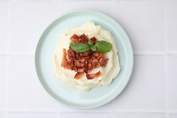 Fried bacon, mashed potato and basil on white tiled table, top view