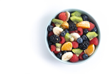 Fruit salad in a blue bowl isolated on white background. Top view. Copy space