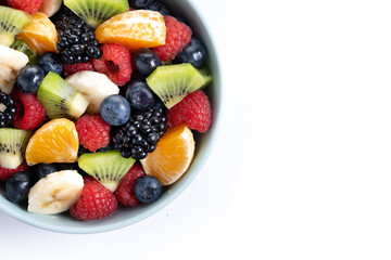 Fruit salad in a blue bowl isolated on white background. Top view. Copy space