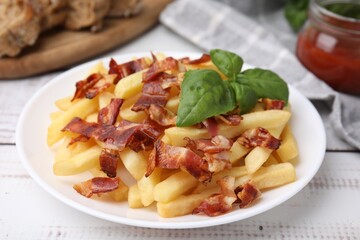 Delicious French fries with slices of bacon and basil on wooden rustic table, closeup