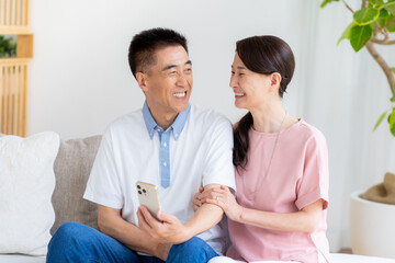 リビングでスマホを見るシニア夫婦