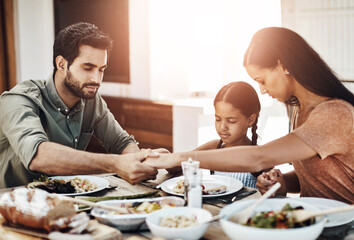 Prayer, family and lunch at table for faith, gratitude and worship together at home. Holding hands, parents and child in dining room for food, support and healthy meal in afternoon for Christianity