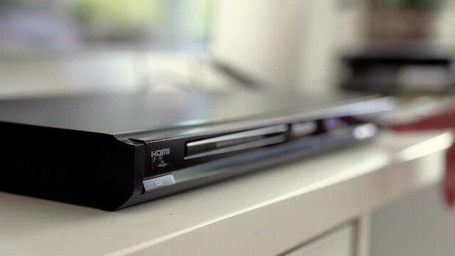 Man puts cd disc  to a video player tray. Physical media concept.