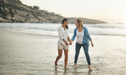 Fototapeta premium Holding hands, couple and water in beach, lesbian and women on sand, vacation and walking with love. Summer, travel and waves in sea, holiday and peace of people, lgbtq and trust in adventure of date