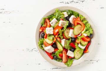 Greek salad of fresh cucumber, tomato, sweet pepper, lettuce, red onion, feta cheese and olives with olive oil. Healthy food. Top view