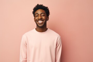 Fototapeta premium Portrait of a joyful man in his 20s showing off a lightweight base layer over solid pastel color wall