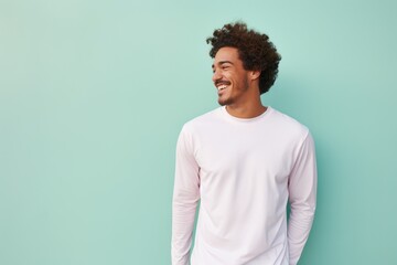 Portrait of a joyful man in his 20s showing off a lightweight base layer on solid pastel color wall