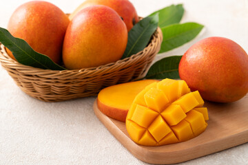 Fresh slice cut juicy mango on gray table background with leaf.