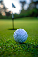 Obraz premium Vibrant golf ball in motion on green course with flagstick in background