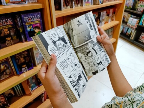Jakarta, Indonesia - June 11, 2024: A child's hand holding and reading a comic book in a bookstore in Jakarta