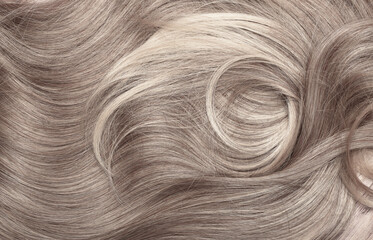 Blond hair close-up as a background. Women's long light brown hair. Beautifully styled wavy shiny...