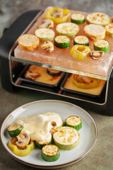 Delicious traditional Swiss melted raclette cheese on diced boiled or baked vegetables served in individual skillets.