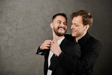 Two men in suits embrace and laugh together, their faces full of joy.