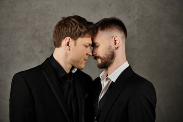 Two men in suits are close together, foreheads touching, in a moment of intimacy.