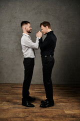 Fototapeta premium Two men in suits stand close, holding hands.