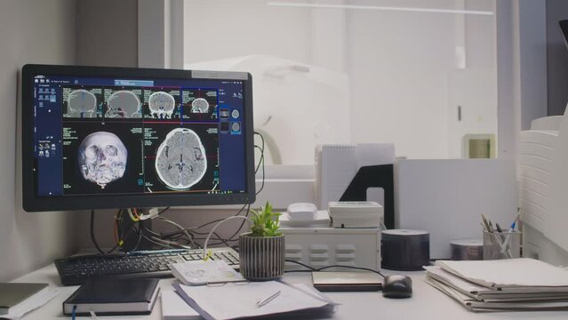 No people shot of empty clinical MRI control room with computer screen displaying digital brain scan, advanced functional imaging equipment in background