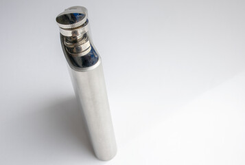 Thin stainless steel flask, close-up, isolated on a light background, side view