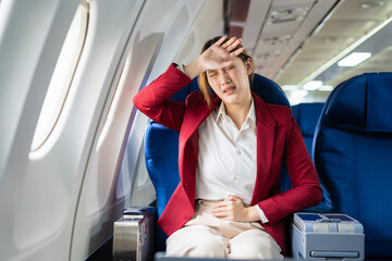 Tired asian woman with headache feeling sick while sitting in the airplane , Passengers near the...