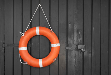 Life.  Red lifebuoy hanging from a black wooden door on the Whitstable seafront.