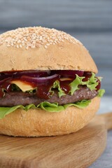 Delicious cheeseburger with lettuce, onion, ketchup and patty on table, closeup