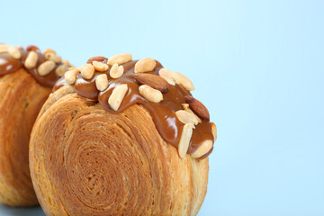 Tasty puff pastry. Supreme croissants with chocolate paste and nuts on light blue background, closeup. Space for text