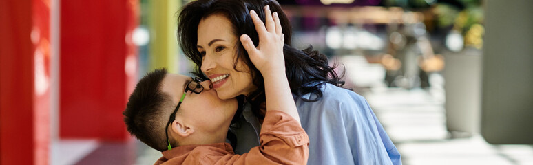 Obraz premium A mother and her son with Down syndrome share a loving moment while walking through a shopping mall.