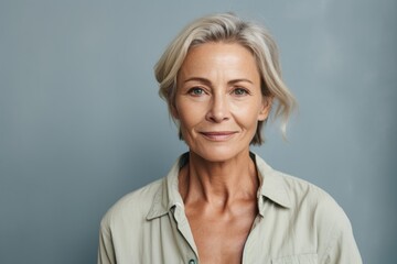 Fototapeta premium Portrait of a tender woman in her 50s sporting a breathable hiking shirt isolated on blank studio backdrop