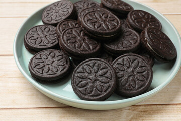 Plate with tasty sandwich cookies on light wooden table, closeup