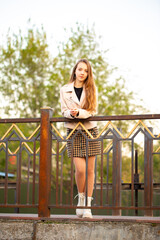 A young smiling girl walks through a spring park in a good mood. Teenage girl, portrait against a background of nature. Fashion style trend.