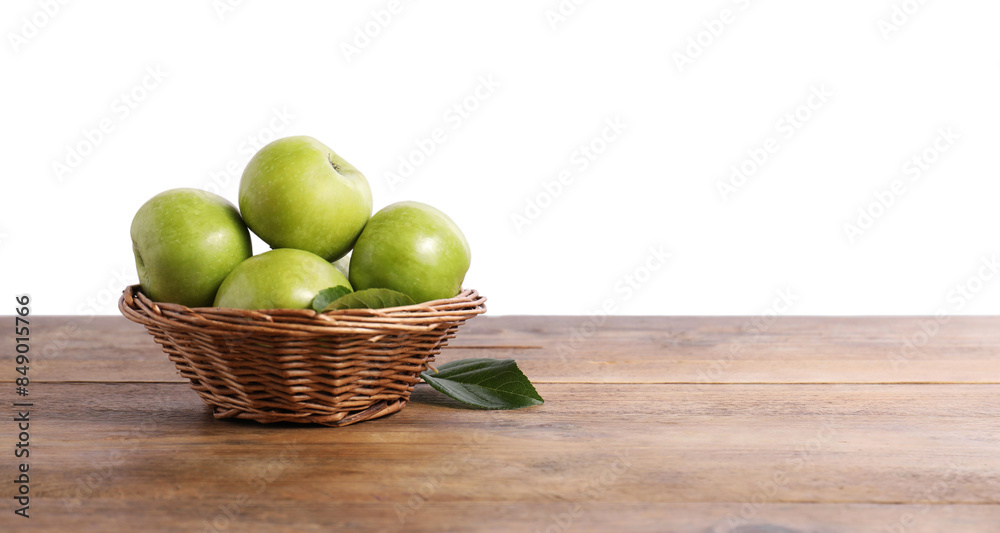 Wall mural ripe green apples in wicker basket on wooden table against white background. space for text - Wall murals
