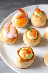 Different delicious puff pastry snacks on stand